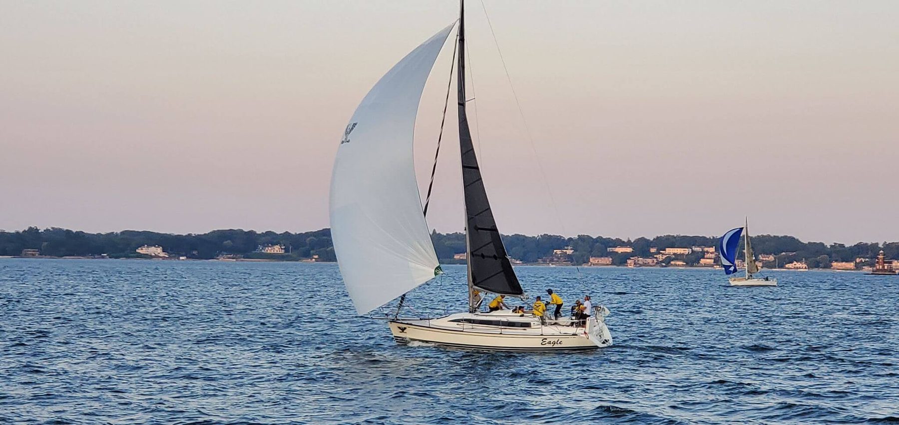 Cruising boat reaching under a Lion mainsail and genoa at dusk